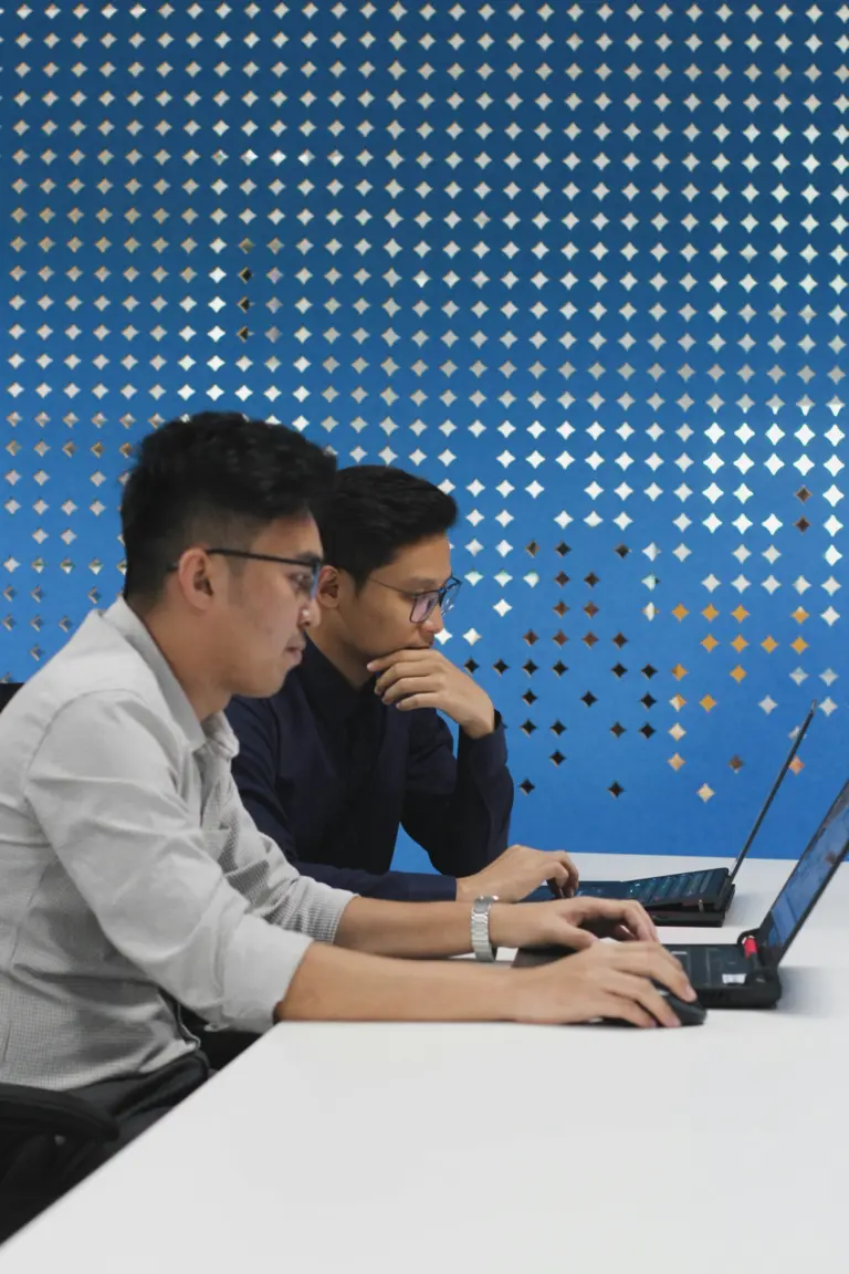 Two engineers working together at a laptop