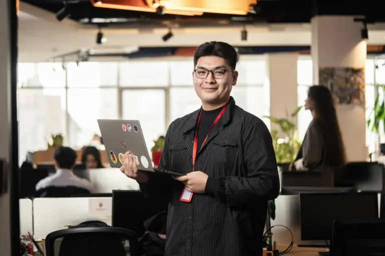 A manager holding a laptop in a modern office
